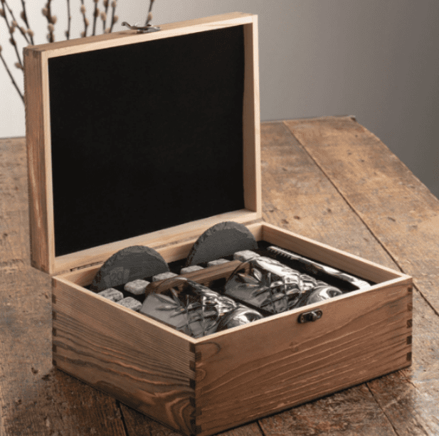 Open wooden keepsake box with personalized items arranged inside on a rustic table.