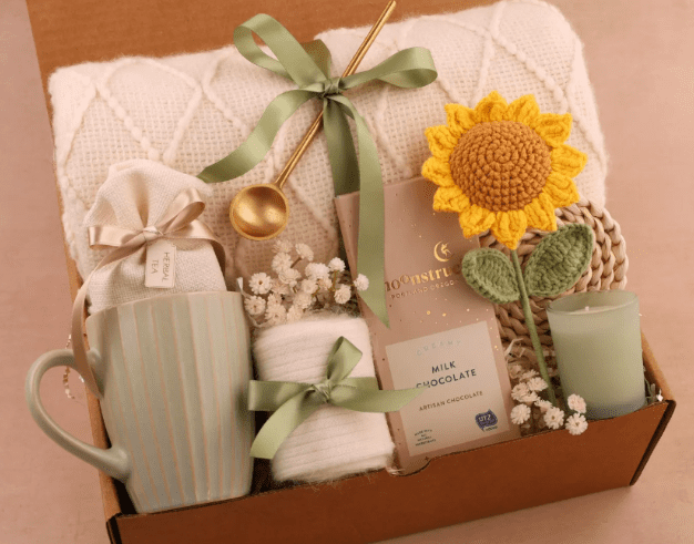 Curated gift box with mug, blanket, candle, chocolate bar, and a crochet sunflower.